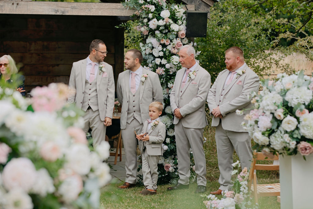 Jack and his groomsmen standing beside the outdoor ceremony flowers